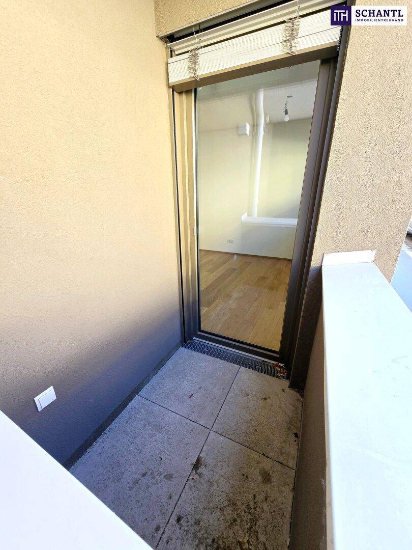 Kleiner Balkon mit Fliesenboden und Blick in den Innenraum durch die Glastür.