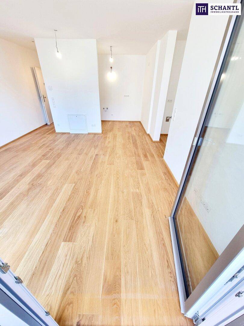 Geräumiger, heller Innenraum mit Holzboden und weißen Wänden, bereit zur Einrichtung.