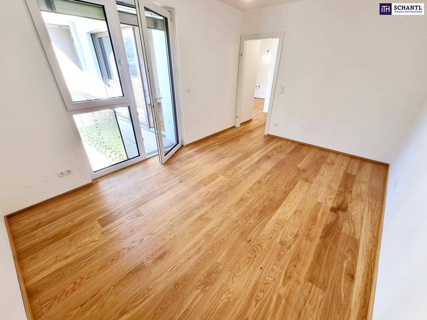 Heller Raum mit Parkettboden und Zugang zu einem weiteren Bereich, ideal für flexible Nutzung.