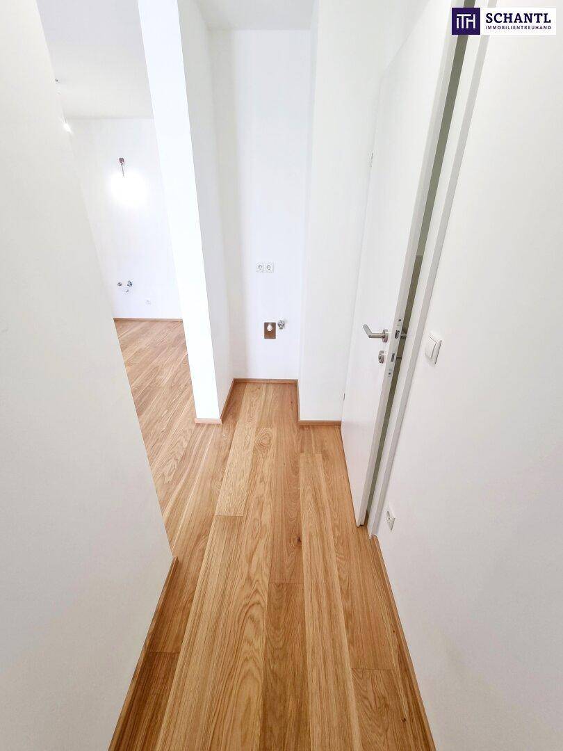 Heller Flur mit durchgehendem Holzparkettboden, der zu den verschiedenen Räumen führt.