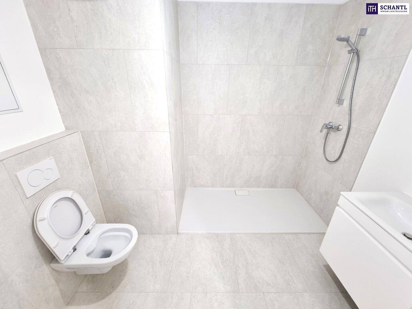Modernes Badezimmer mit hellgrauen Fliesen, wandhängendem WC und ebenerdiger Dusche.