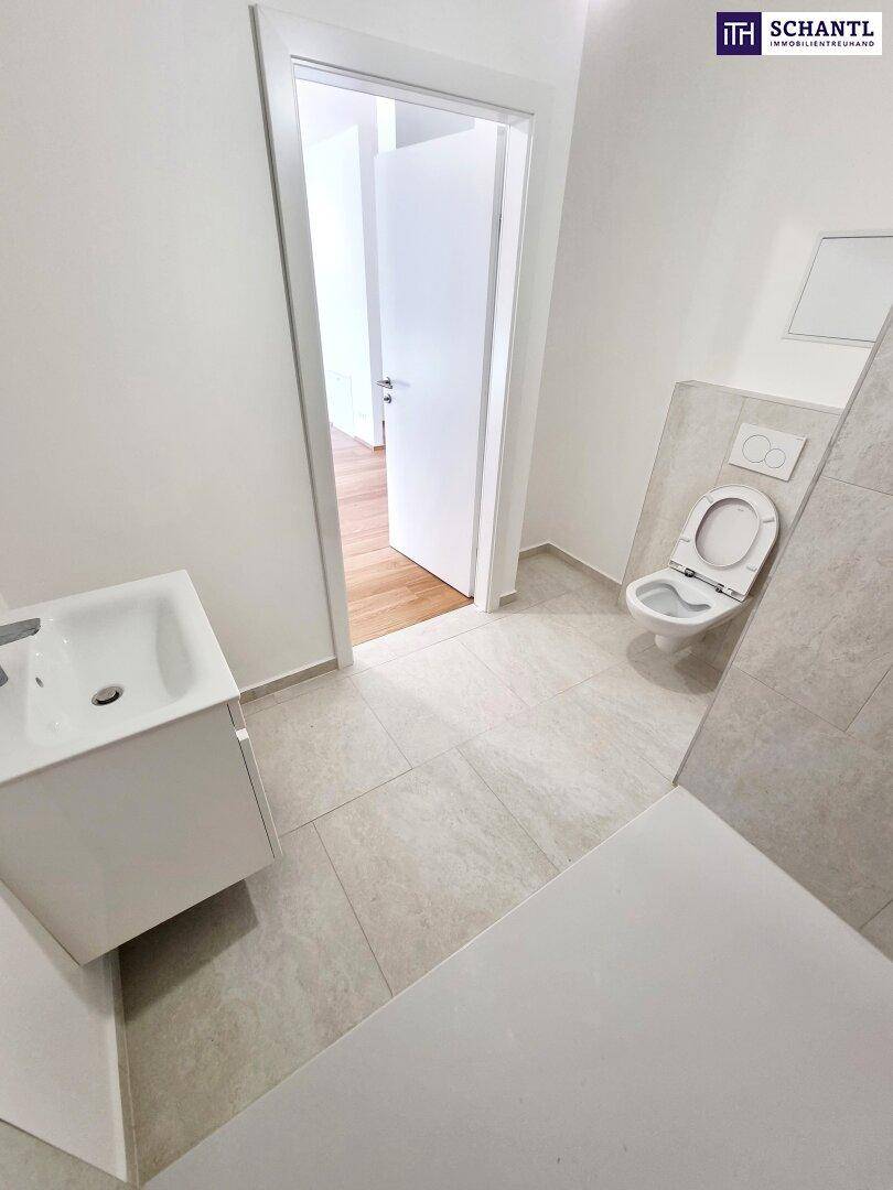 Helles Badezimmer mit modernem Waschtisch, WC und Zugang zu einem weiteren Raum.