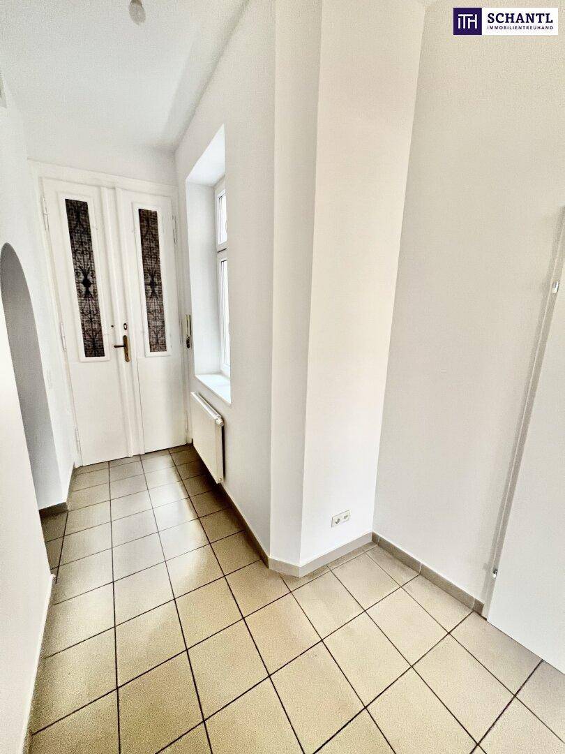 Eingangsbereich mit hellen Fliesen, weißen Wänden und einem Fenster, das für natürliche Belichtung sorgt.