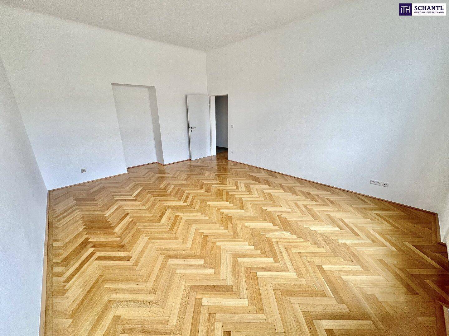 Geräumiger, leerer Raum mit Fischgrätparkettboden und weißen Wänden, bereit zur individuellen Gestaltung.