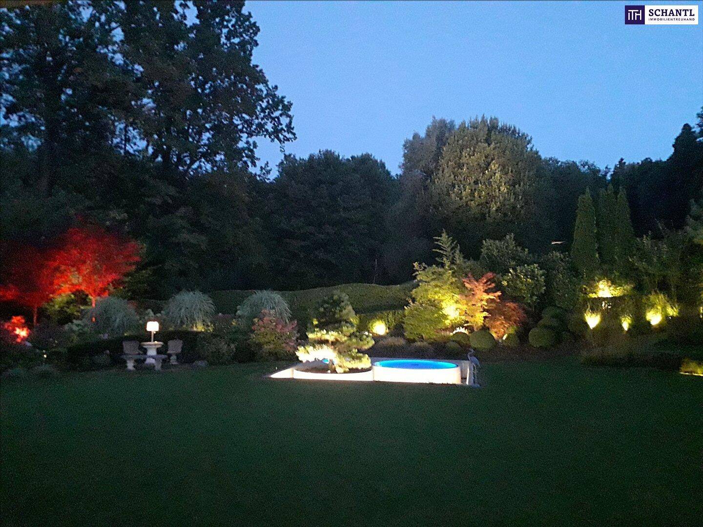 Gartenlandschaft in der Abenddämmerung mit stimmungsvoller Beleuchtung und einem kleinen Pool.