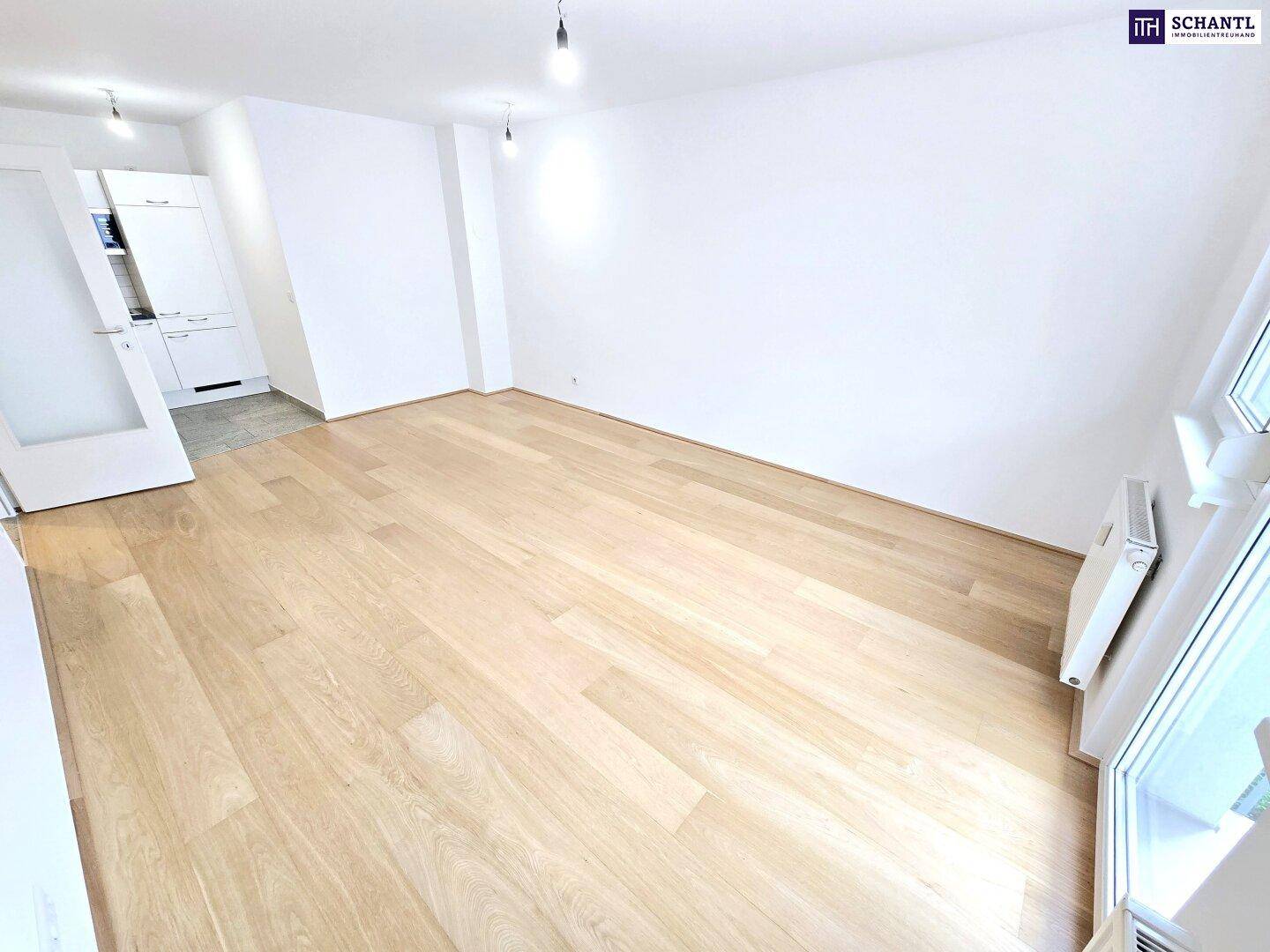 Helles, leeres Wohnzimmer mit hellem Holzparkett und weiß gestrichenen Wänden, bereit zur Einrichtung.