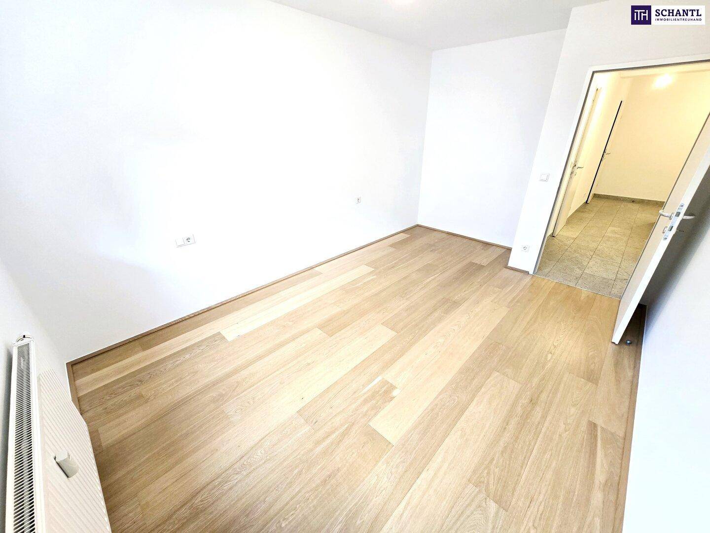 Helles Zimmer mit Holzboden und weiß gestrichenen Wänden, ideal als Schlafzimmer oder Arbeitsbereich.