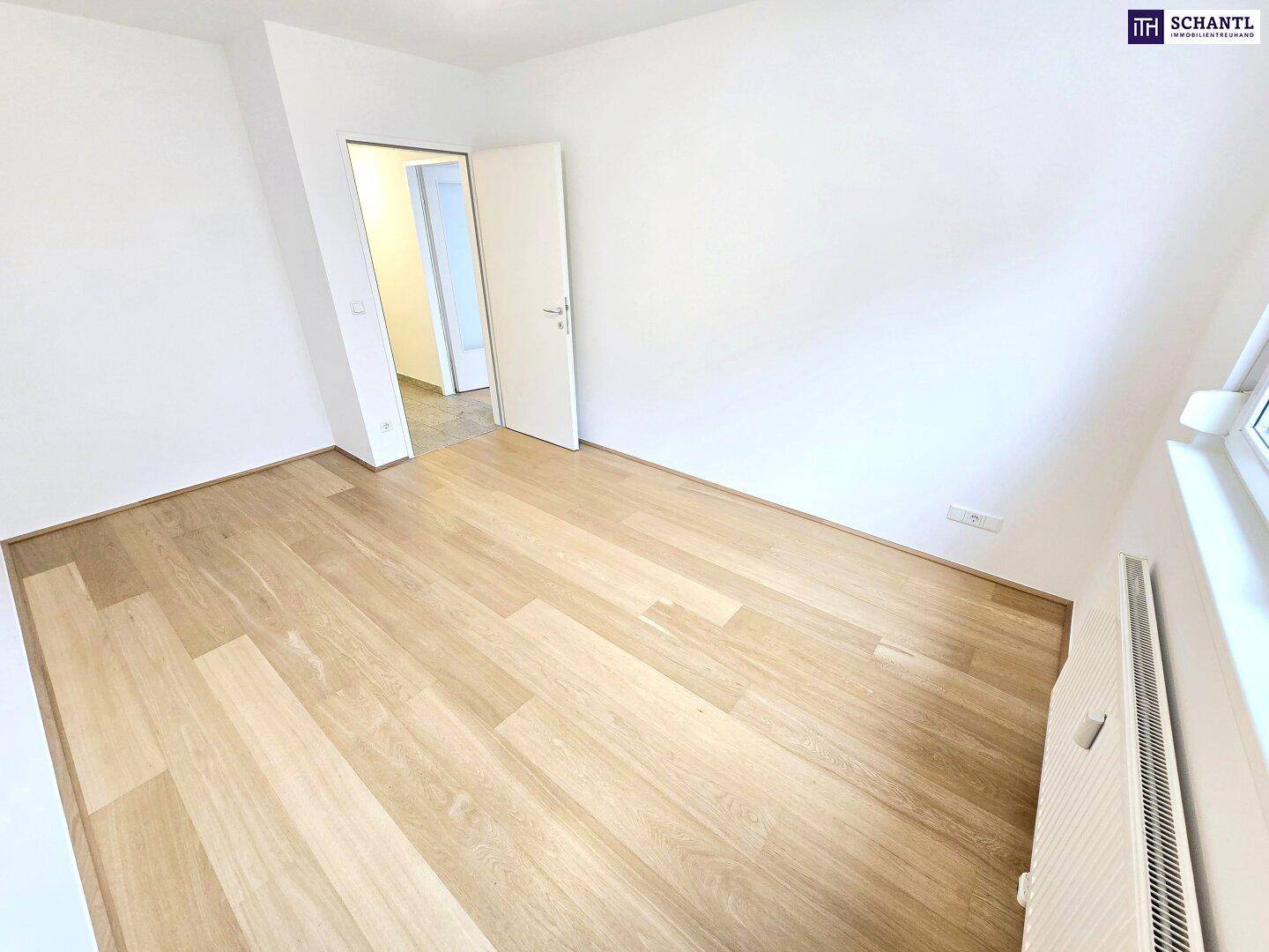 Freundliches Zimmer mit hellem Parkettboden und großen Fenstern, die viel Tageslicht hereinlassen.