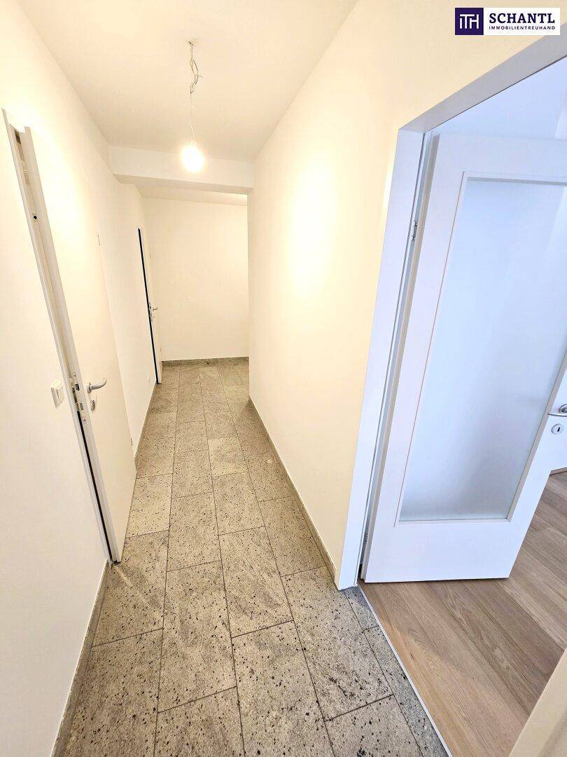 Langer Flur mit Fliesenboden und weiß gestrichenen Wänden, der die verschiedenen Räume der Wohnung verbindet.