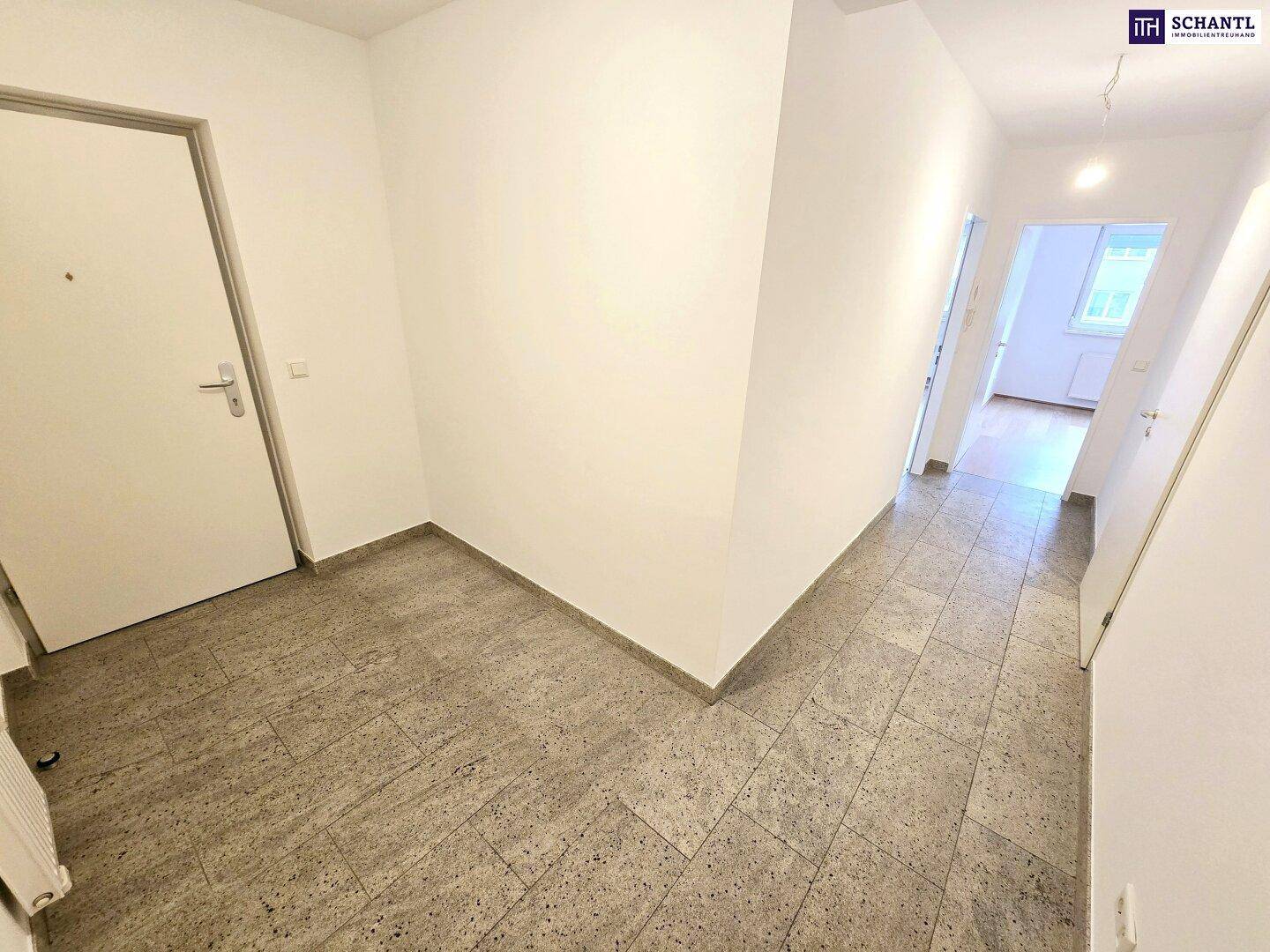 Geräumiger Flur mit Fliesenboden und weiß gestrichenen Wänden, der verschiedene Wohnbereiche verbindet.