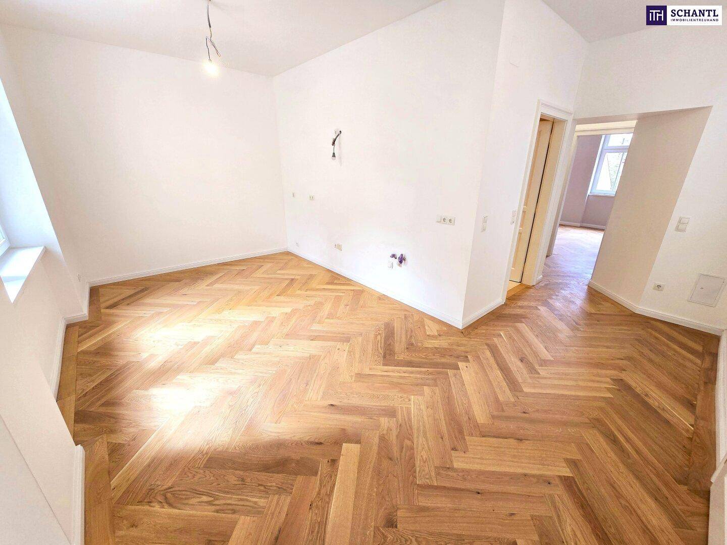 Leeres Zimmer mit Fischgrätparkett und weißen Wänden, bereit für individuelle Einrichtungsideen.