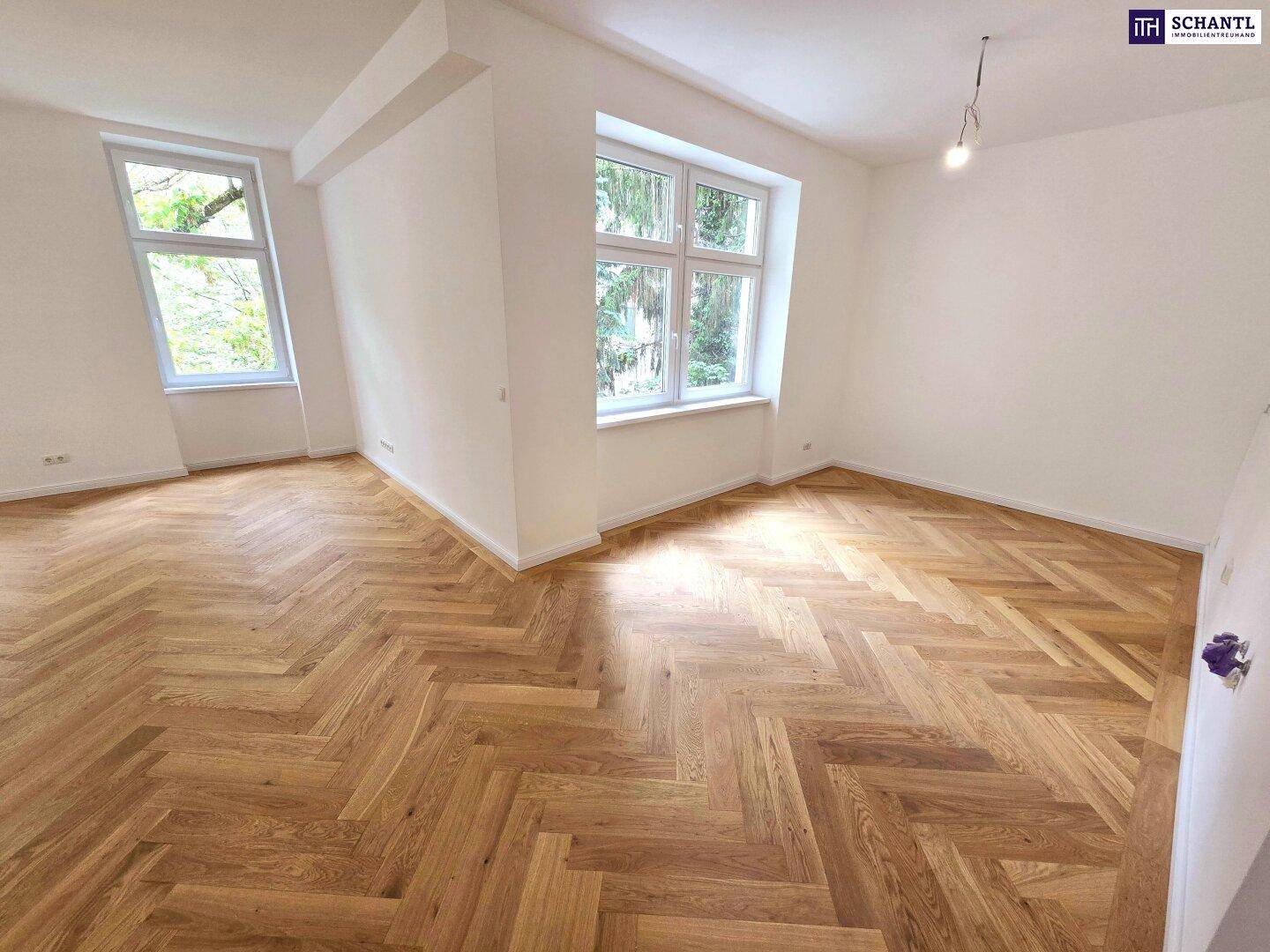 Geräumiges Zimmer mit Fischgrätparkett und zwei Fenstern, die viel Licht und Grünblick bieten.