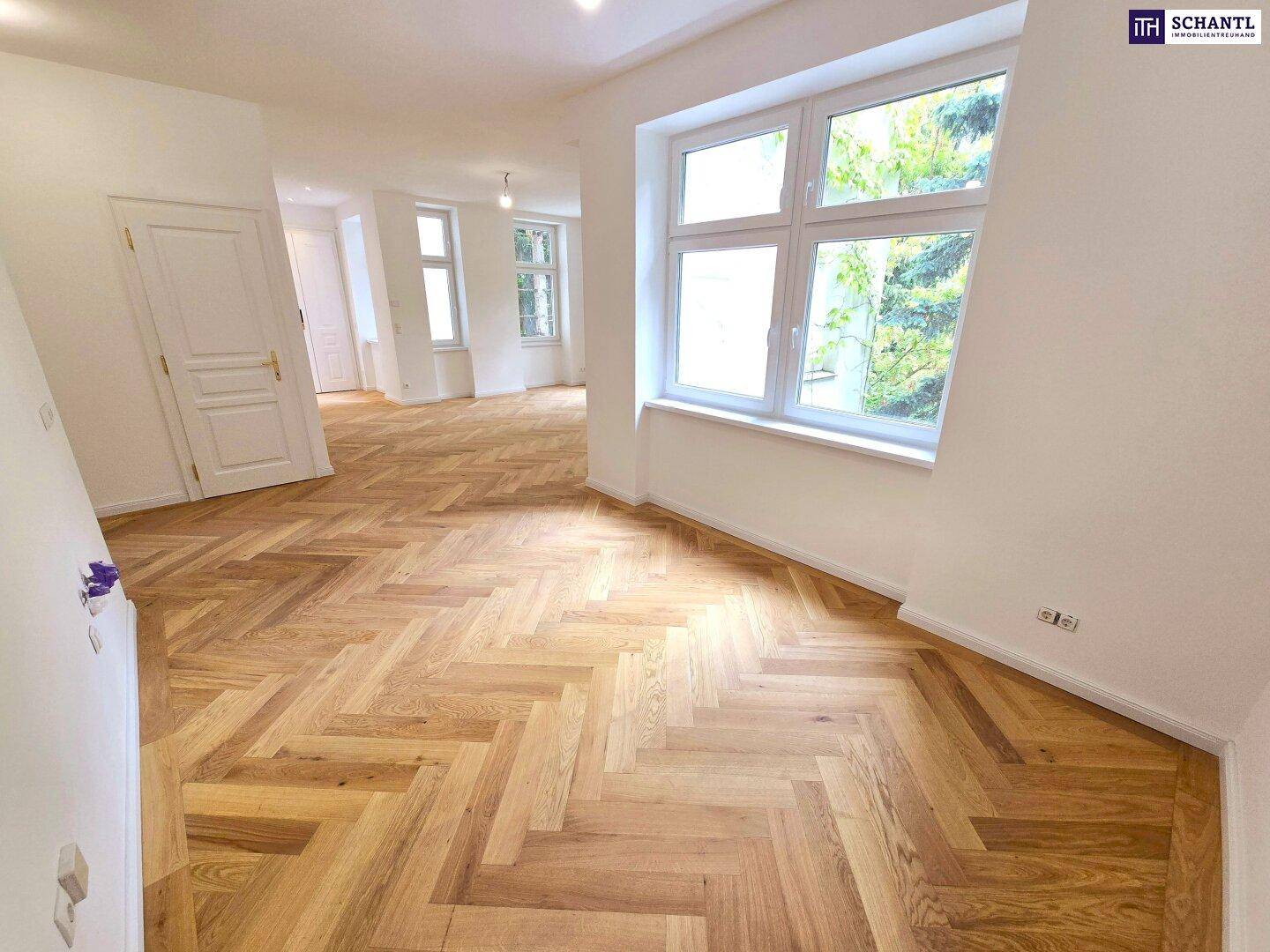 Großes, helles Zimmer mit Fischgrätparkett und weitem Blick durch die Fenster.