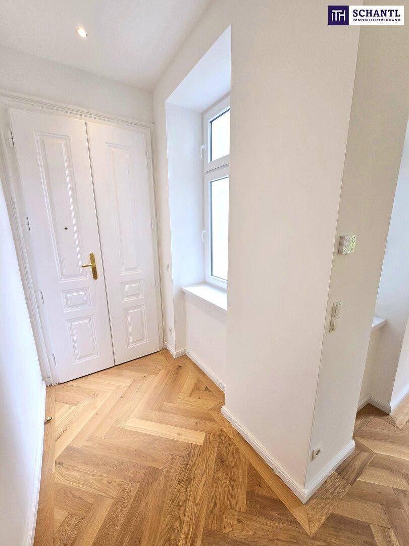 Heller Eingangsbereich mit Fischgrätparkett und einer Doppeltür, die in die Wohnung führt.