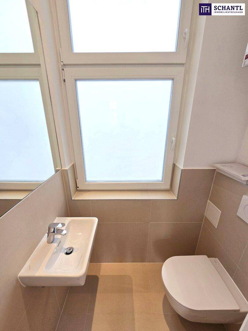 Modernes Gäste-WC mit Wand-WC, kleinem Waschbecken und Fenster für Tageslicht.