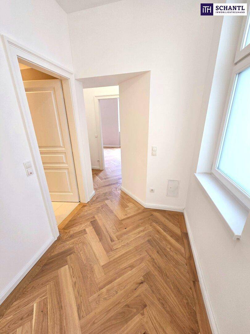 Heller Flur mit Fischgrätparkett, der zu verschiedenen Zimmern der Wohnung führt.