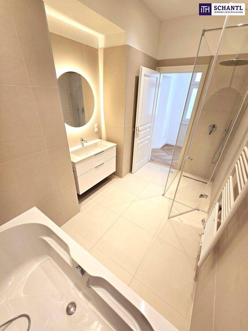 Elegantes Badezimmer mit Badewanne, begehbarer Dusche und beleuchtetem Spiegel über dem Waschbecken.