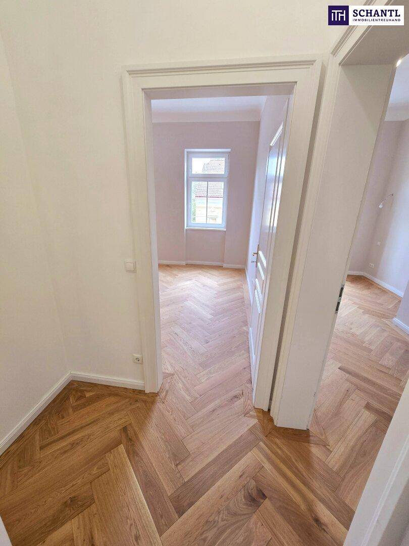 Heller Flur mit Fischgrätparkett, der den Zugang zu einem weiteren Zimmer ermöglicht.