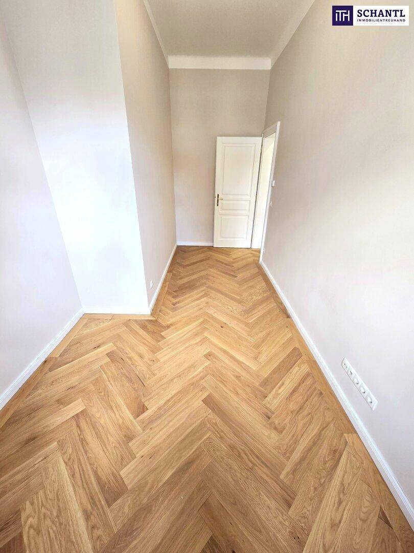 Langer, heller Raum mit Fischgrätparkett und einer Tür am Ende, ideal als Flur oder Ankleide.