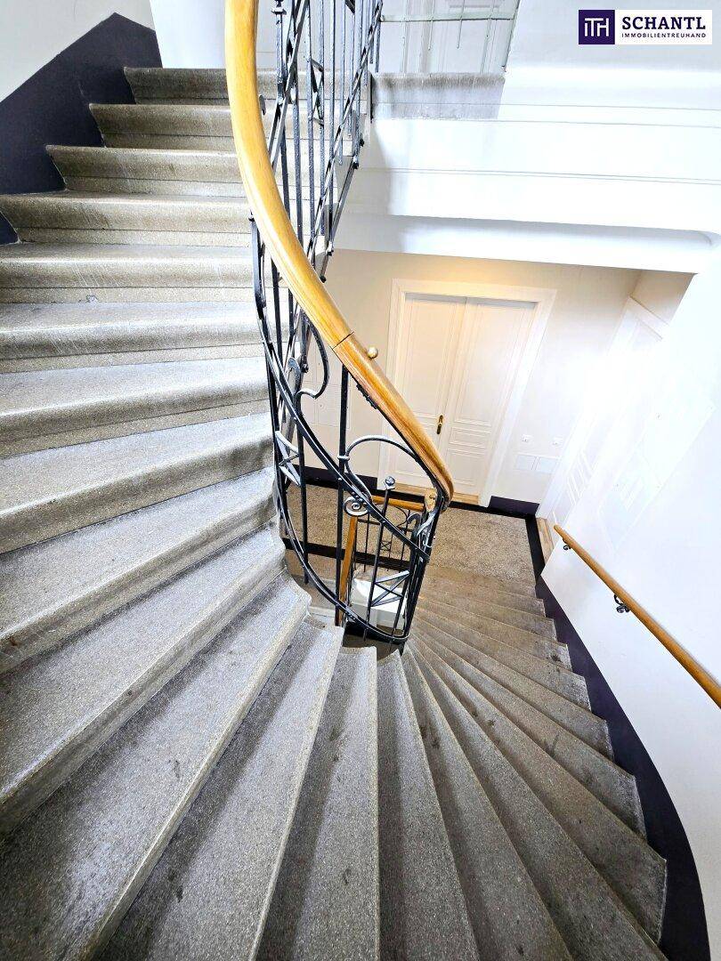Historisches Treppenhaus mit Steinstufen und schmiedeeisernem Geländer, das Eleganz ausstrahlt.