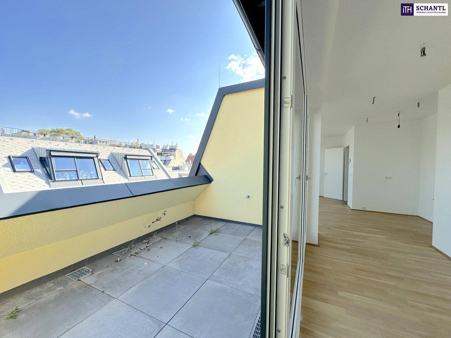 Geräumige Dachterrasse mit Fliesenboden und Blick über die Dächer der Stadt.