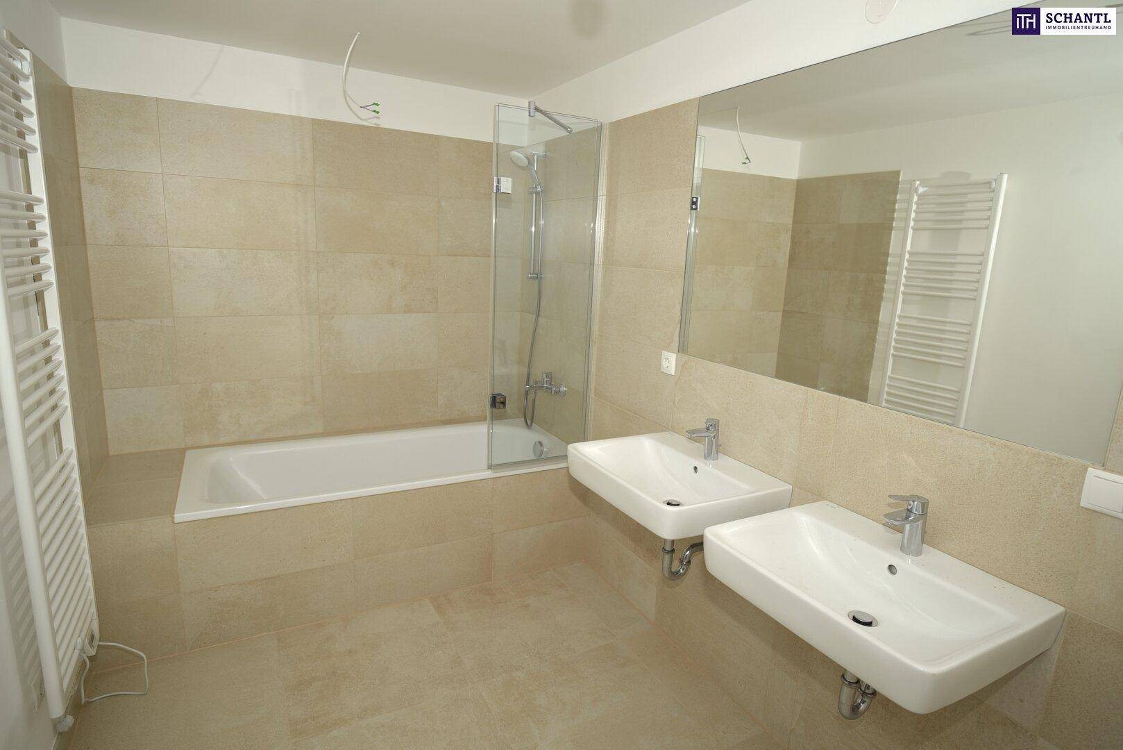 Modernes Badezimmer mit beigen Fliesen, Badewanne, Doppelwaschbecken und großem Spiegel.