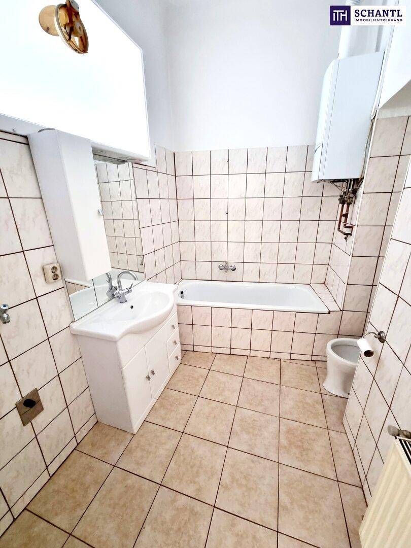 Funktionales Badezimmer mit Badewanne, Waschbecken und Wandfliesen, ausgestattet mit Boiler.