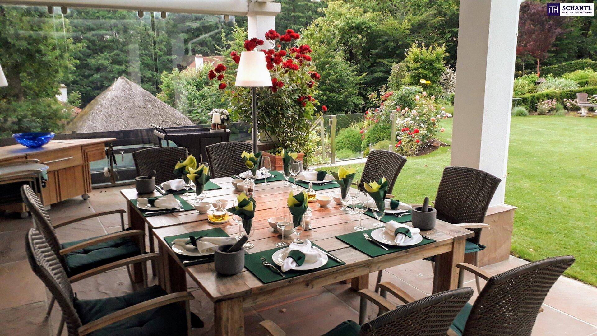 Große überdachte Terrasse mit elegant gedecktem Esstisch und Blick auf den gepflegten Garten.