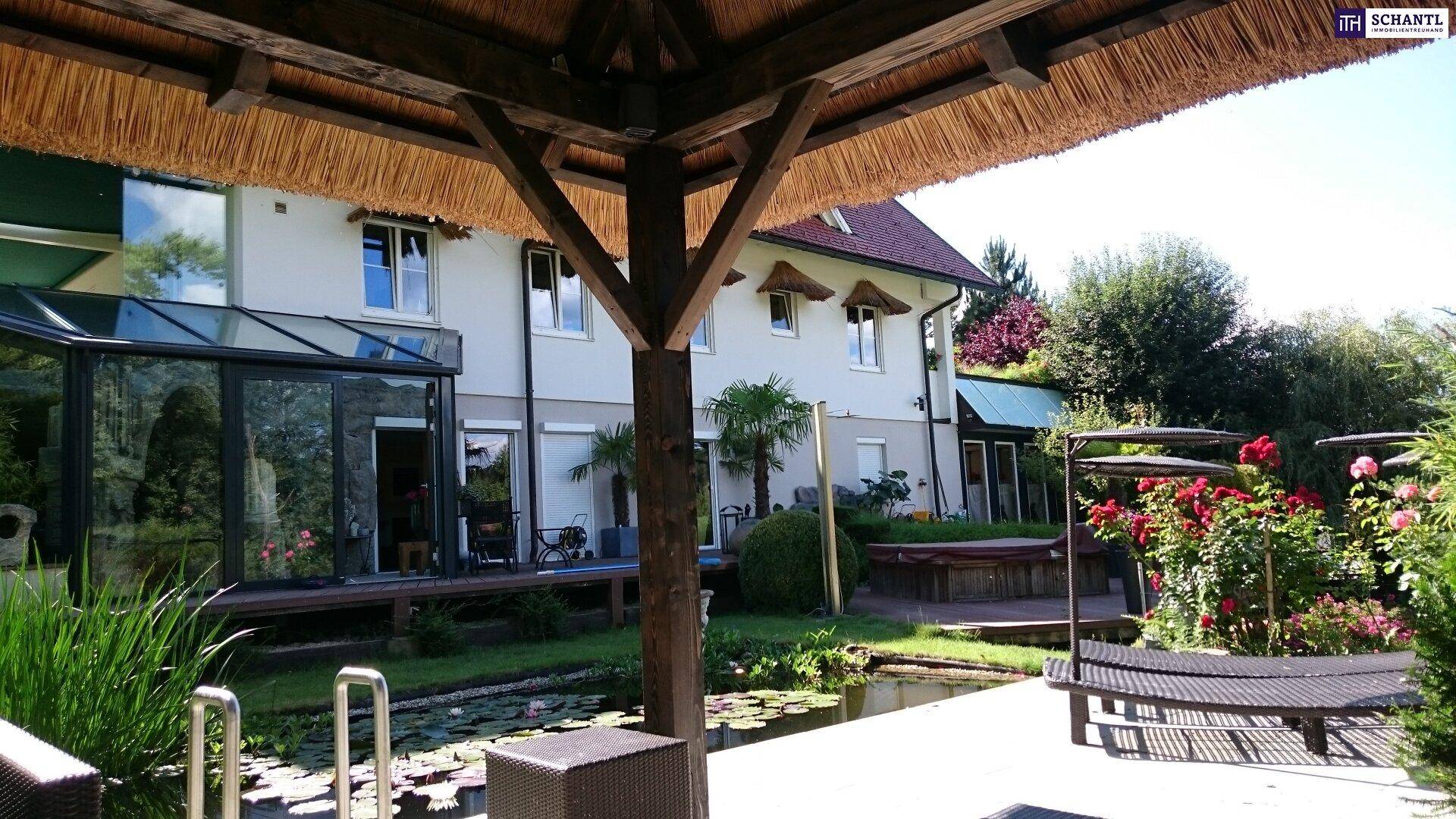 Rückseite des Hauses mit Teich, Liegeflächen und einem gemütlichen Strohdach-Pavillon im Garten.