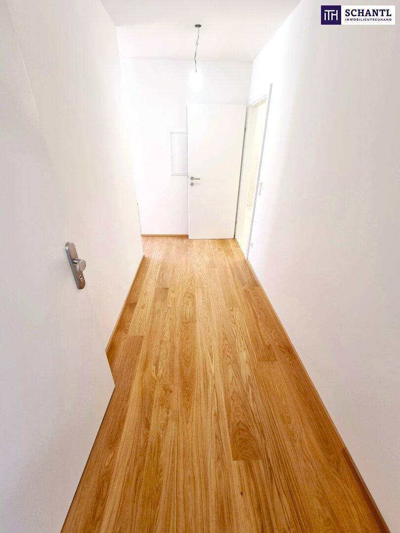 Langer, heller Flur mit Holzboden und mehreren Türen zu den Zimmern.