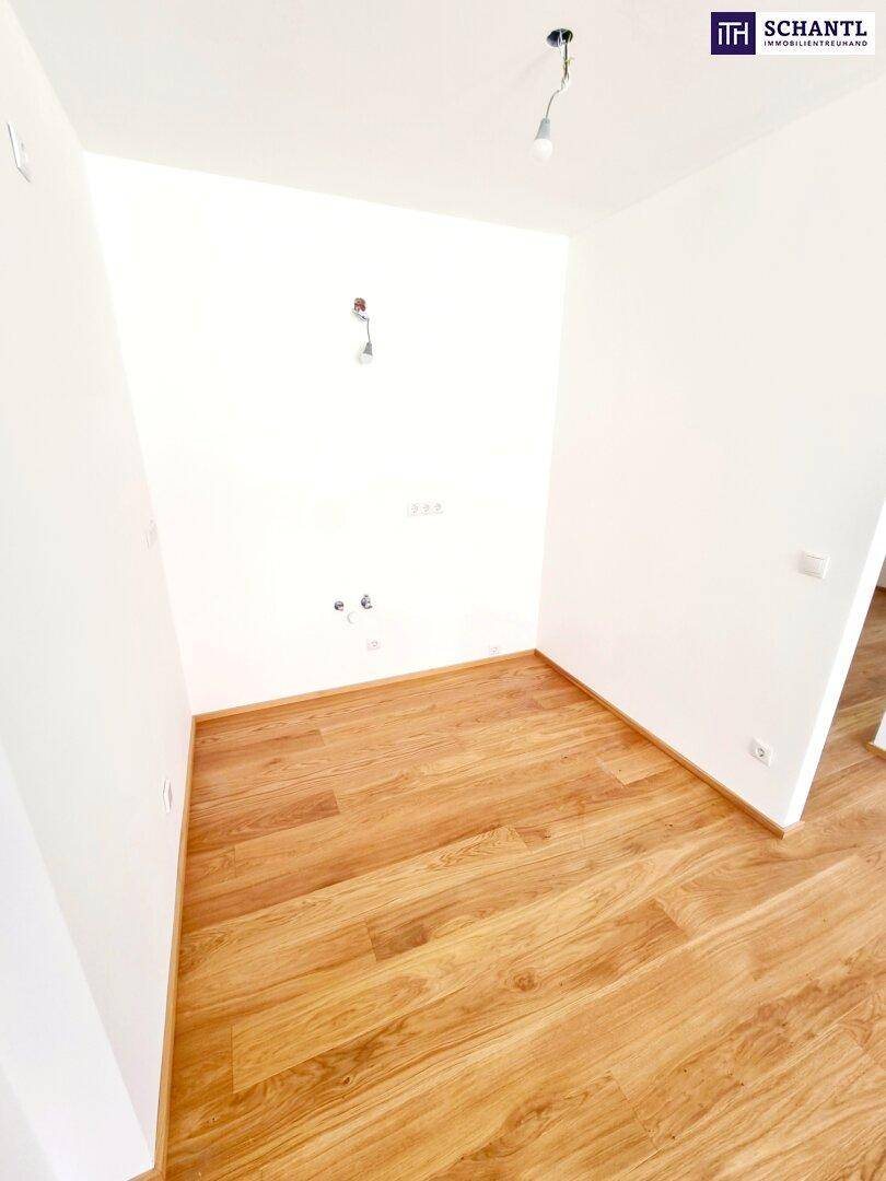 Leerer Raum mit Holzboden und Anschlüssen für eine zukünftige Küche.