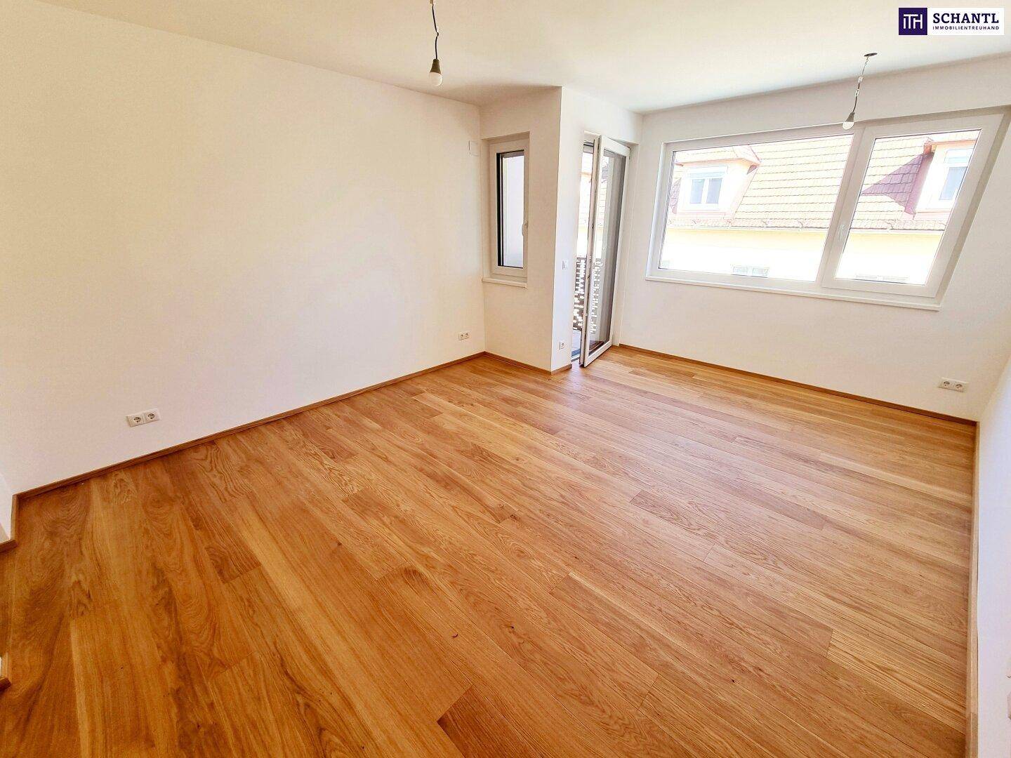 Geräumiges Zimmer mit Holzboden, großen Fenstern und Zugang zum Außenbereich.