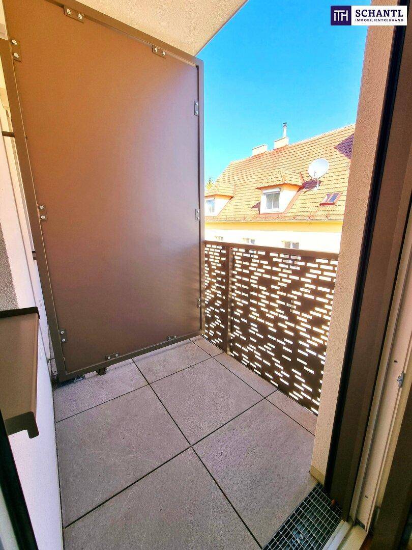 Kleiner Balkon mit Fliesenboden und moderner Metallbrüstung, Blick auf Dächer.