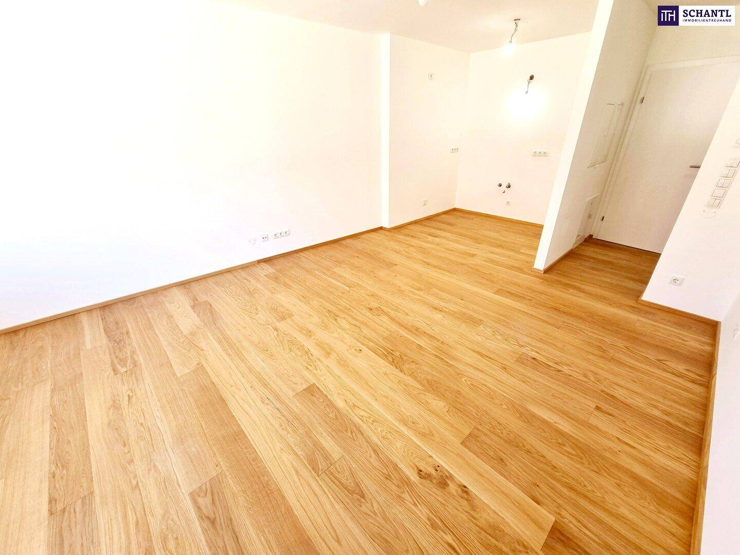 Unmöblierter Raum mit hellem Holzboden und weißen Wänden, bereit zum Einzug.