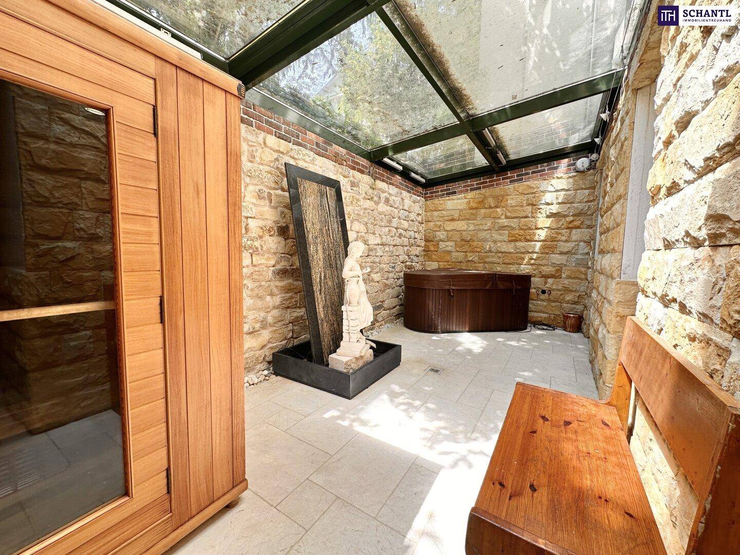 Privater Wellnessbereich mit Sauna, Whirlpool und Steinwänden unter Glasdach.