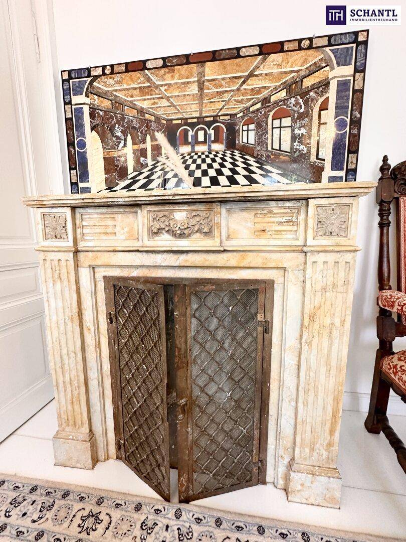 Antiker Kamin mit aufwendigen Verzierungen und einem dekorativen Kunstwerk darüber.