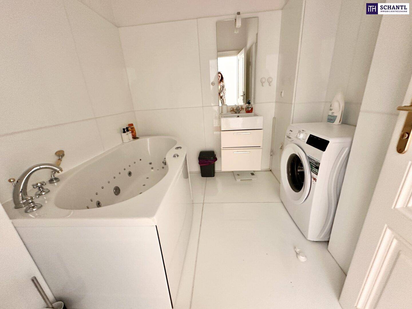 Modernes Badezimmer mit Whirlpool-Badewanne, Waschmaschine und weißen Fliesen.