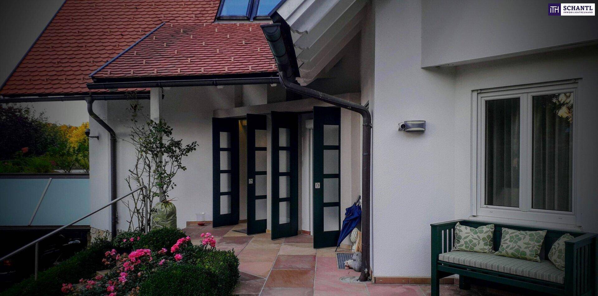 Eingangsbereich des Hauses mit modernen Falttüren und einer kleinen Sitzbank im Freien.