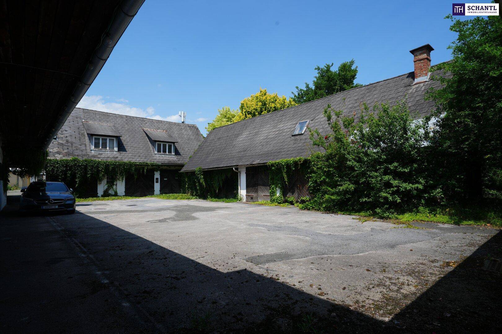 Großer gepflasterter Innenhof mit Parkplätzen, umgeben von alten Gebäuden und viel Grün, bietet viel Raum.