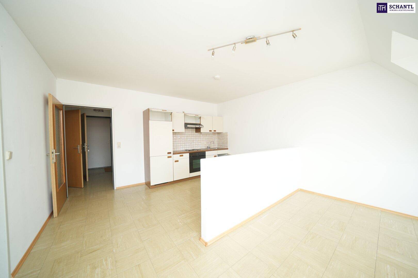 Offener Wohnbereich mit kleiner Einbauküche und Laminatboden, ideal für Singles oder Paare, hell und funktional.