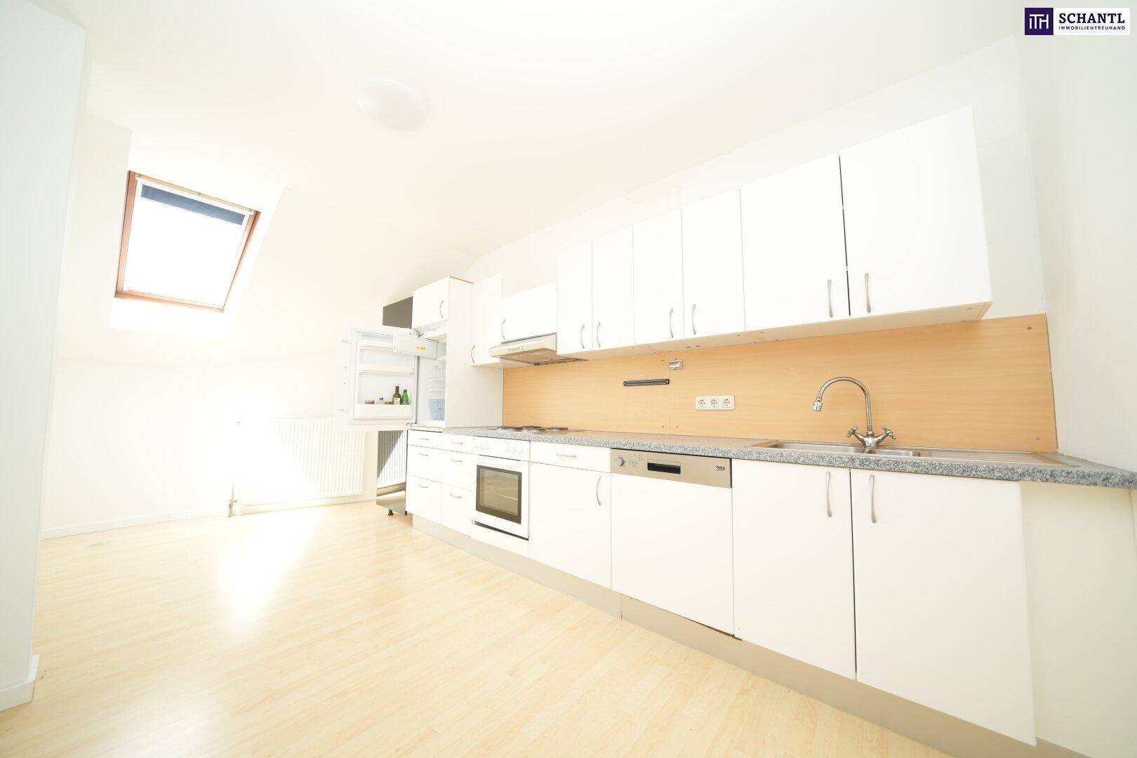 Moderne offene Küche mit weißen Schränken, Laminatboden und Dachfenster, sehr hell und einladend.