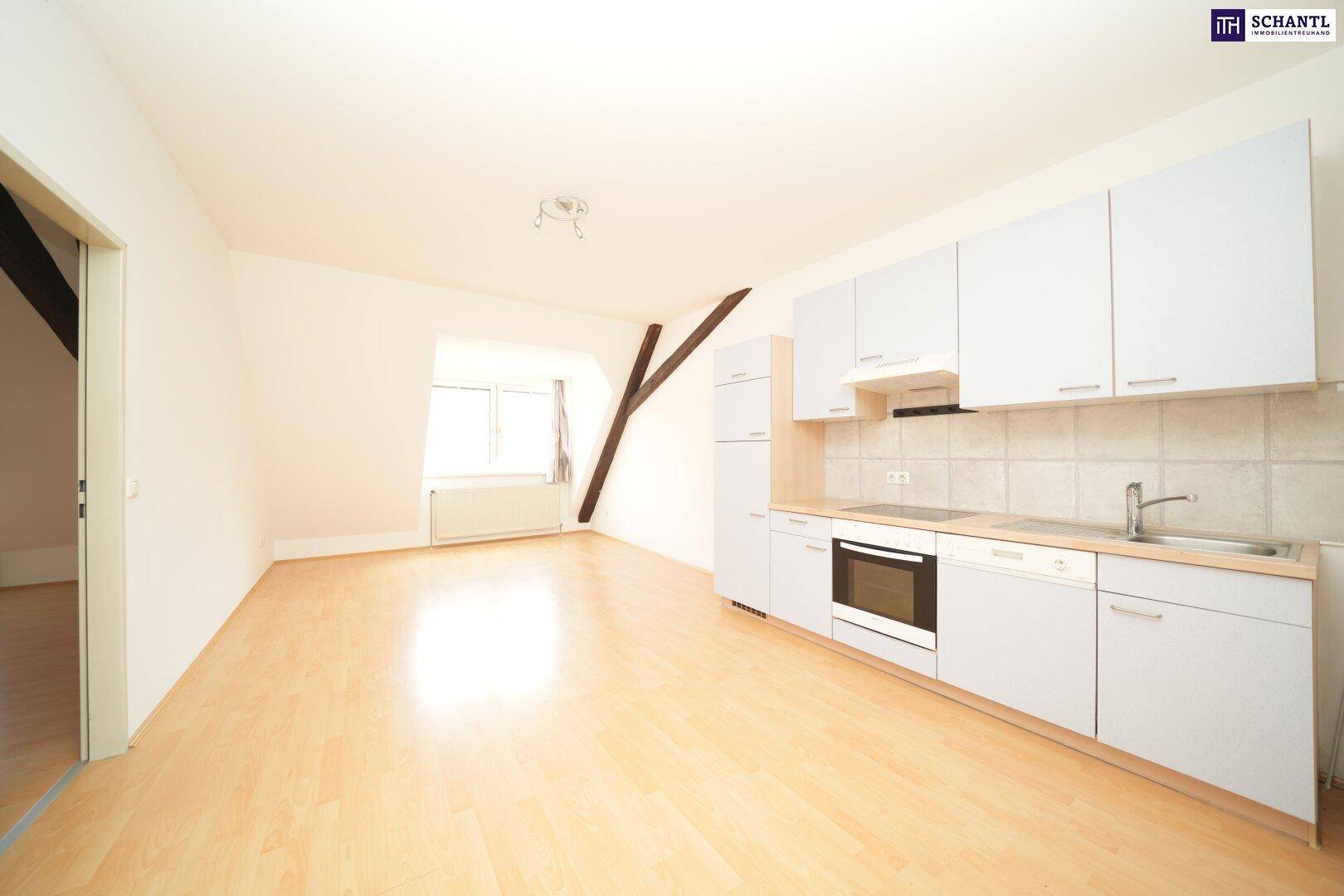 Helle Dachgeschosswohnung mit offener Küche, Laminatboden und sichtbaren Holzbalken, ideal für modernes Wohnen.