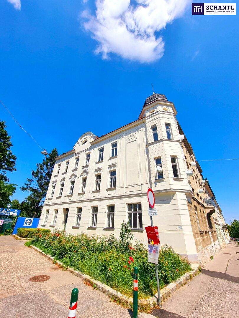 Elegantes Eckgebäude mit klassischer Architektur und gepflegter Grünfläche im Vordergrund.