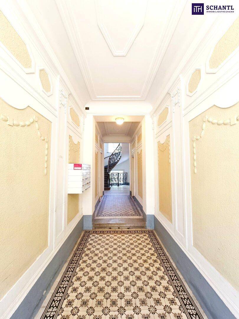 Historischer Hausflur mit aufwendigen Stuckverzierungen und gemustertem Fliesenboden.