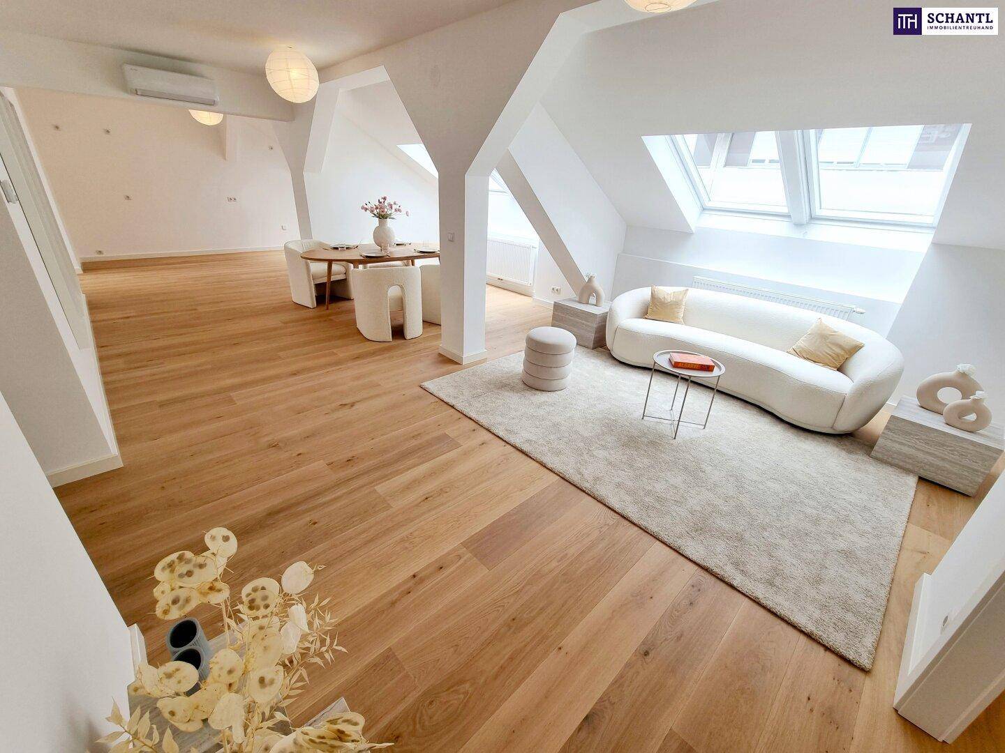 Gemütlicher Wohn- und Essbereich im Dachgeschoss mit modernem Sofa, Teppich und Holzboden.