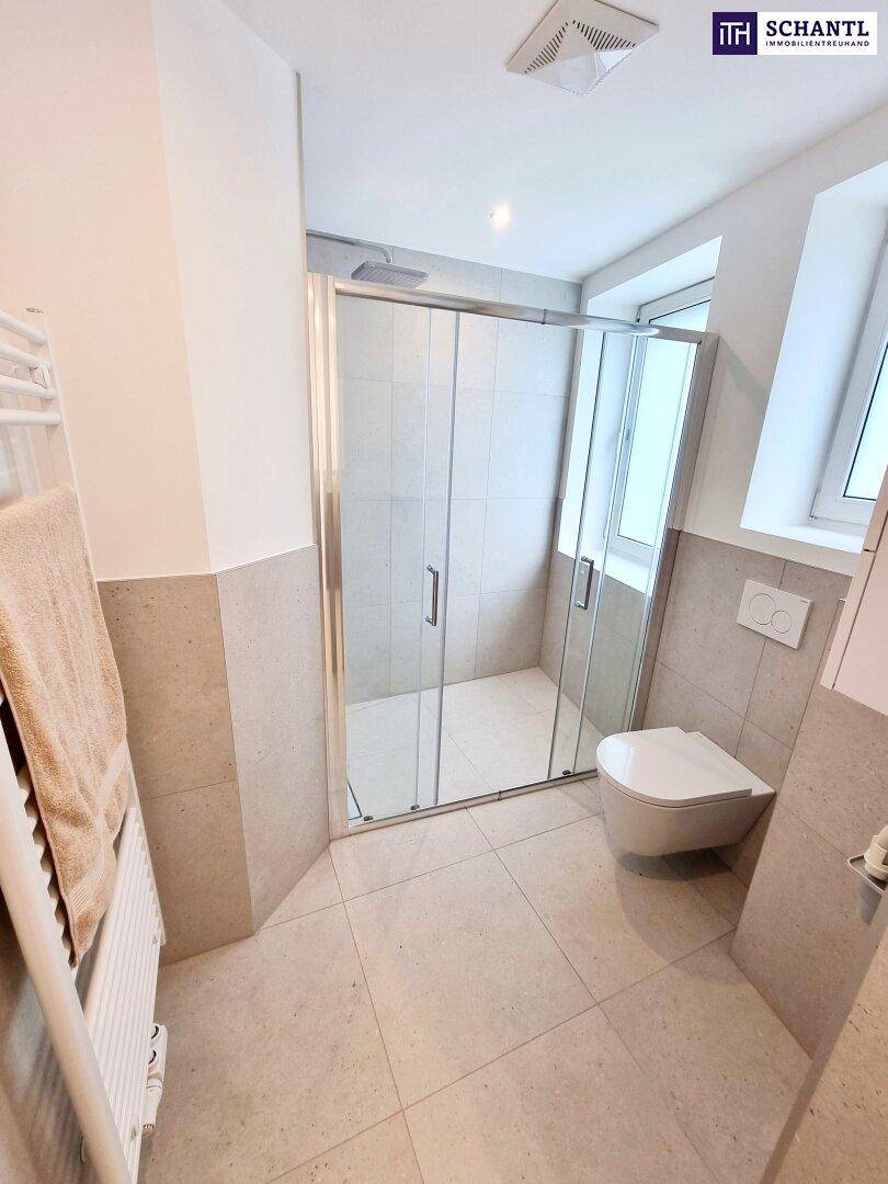 Modernes Badezimmer mit Duschkabine, WC, Handtuchheizkörper und Fenster für natürliche Belüftung.