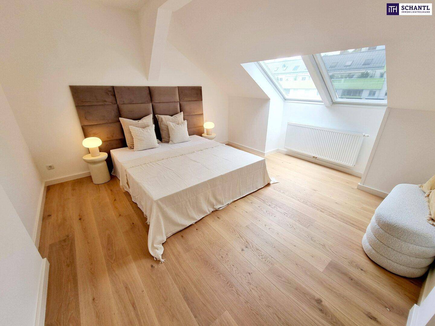 Helles Schlafzimmer im Dachgeschoss mit Holzboden, großem Bett und Dachfenstern für viel Licht.