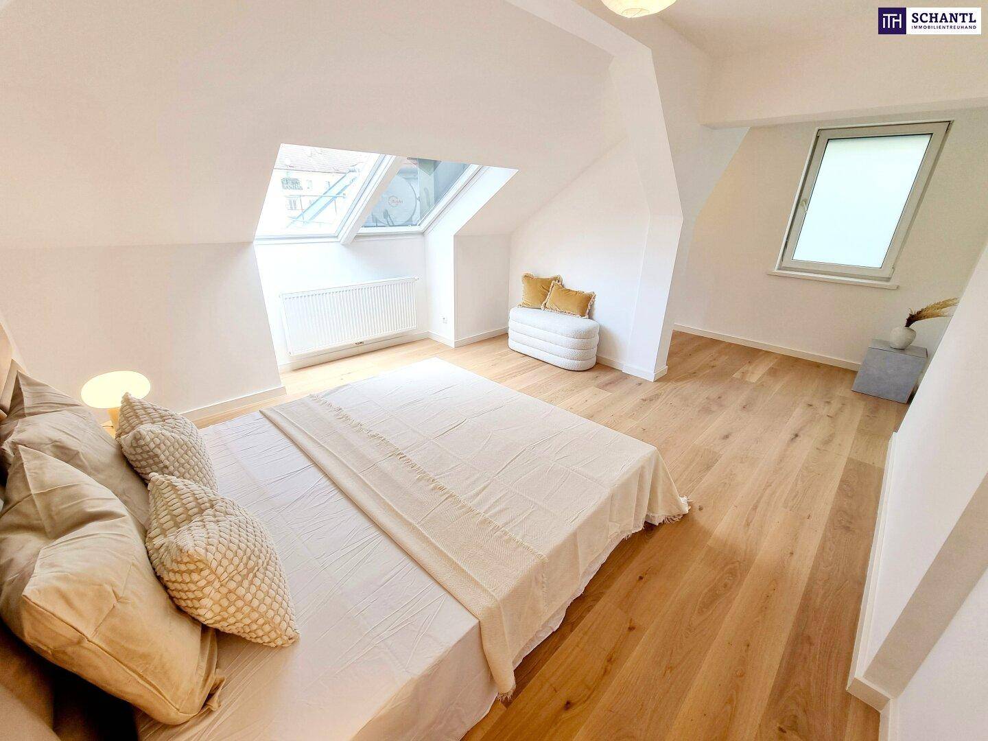 Helles Schlafzimmer im Dachgeschoss mit Holzboden, großem Bett und Dachfenstern.