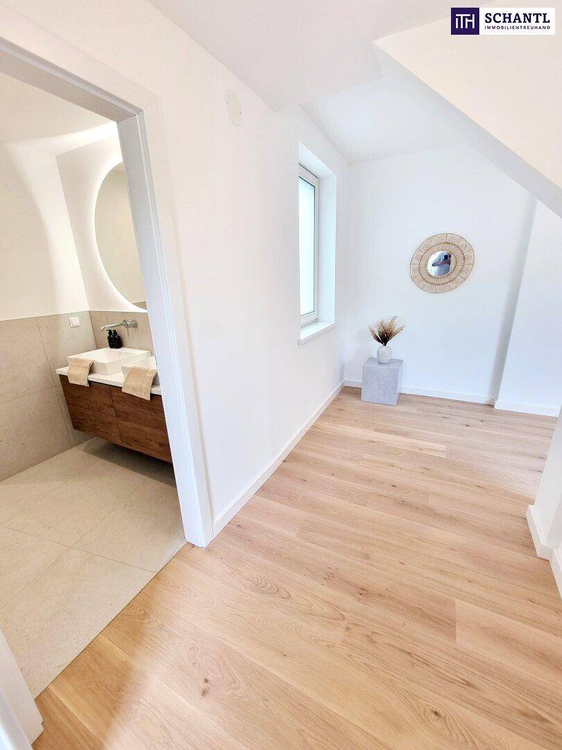 Heller Flur mit Holzboden, der zu einem modernen Badezimmer mit Doppelwaschbecken führt.