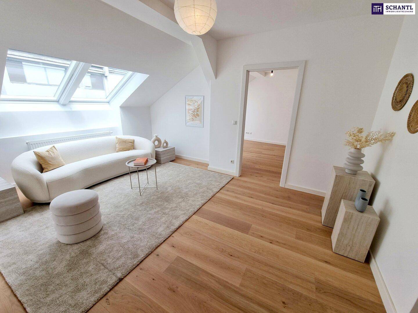 Stilvolles Wohnzimmer im Dachgeschoss mit Sofa, Teppich und Blick in einen angrenzenden Raum.